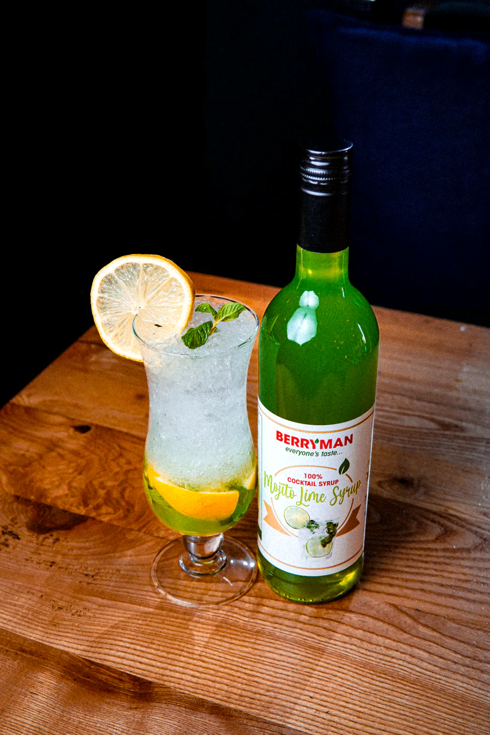 Cocktail next to a bottle of cordial, styled for social